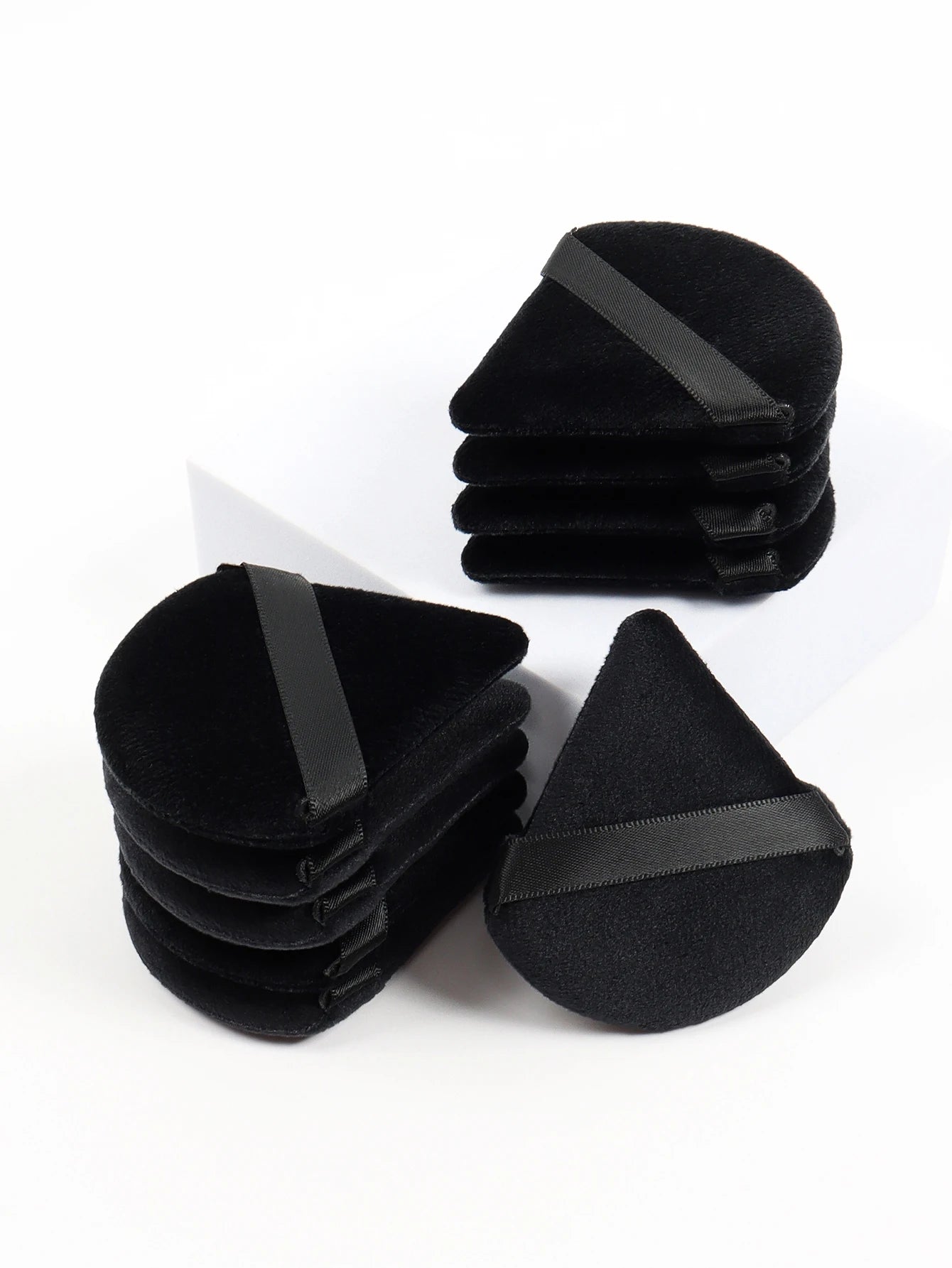 Black triangle-shaped velvet makeup sponge from amzzonstore, soft foundation applicator for flawless facial makeup blending.